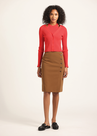 Woman wearing a red cardigan and brown skirt on a white background
