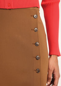 Brown button-up skirt with a red sweater sleeve in the background