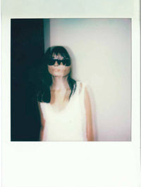 Polaroid-style photo of a person wearing sunglasses and a white sleeveless top.