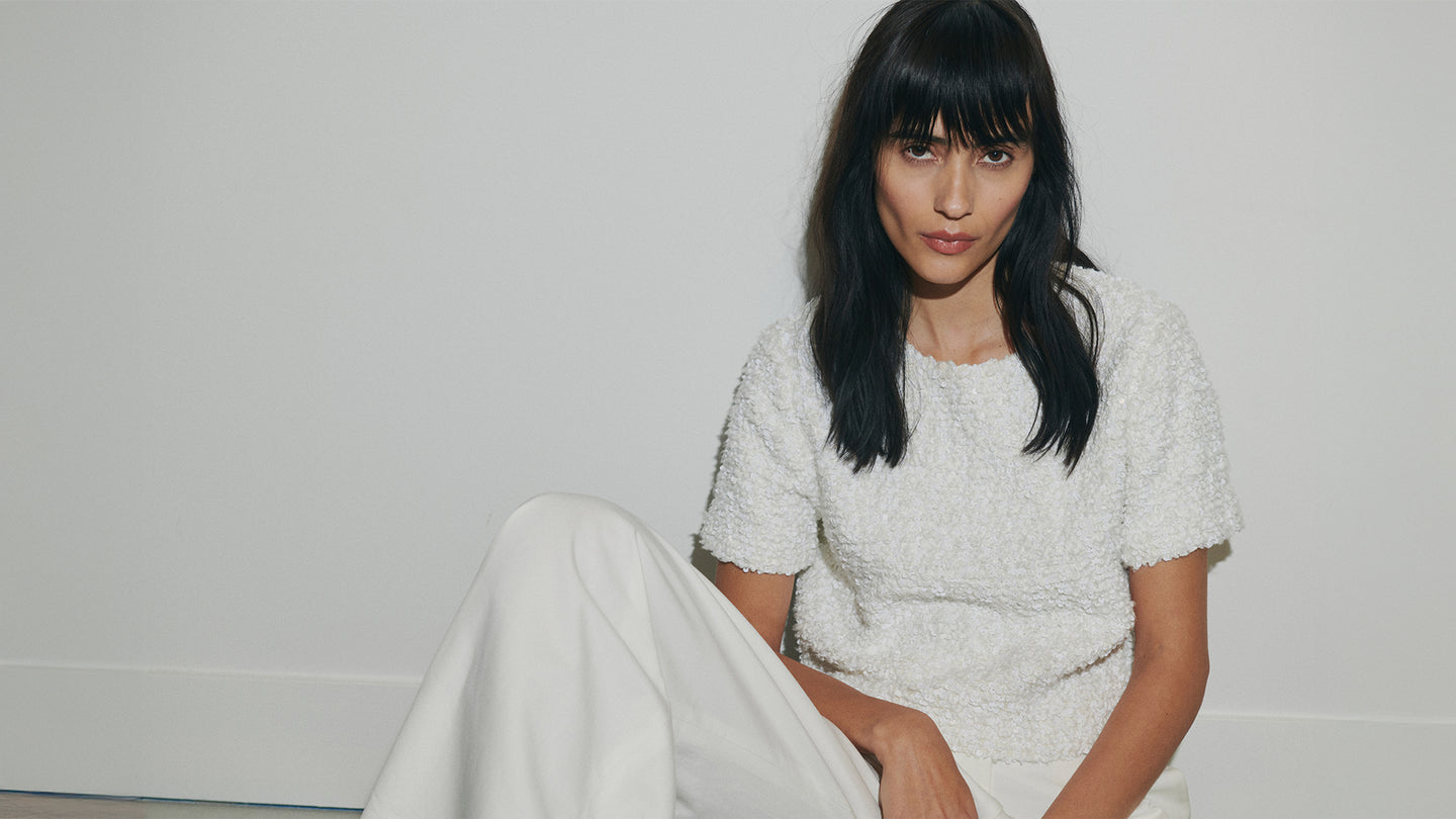 woman wearing all white sitting on floor infront of white wall