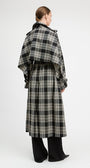 A model shown from the back wearing a long black and beige plaid coat with wide lapels and a self-tie belt, paired with black wide-leg trousers, against a plain light gray studio background.