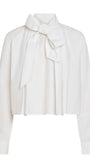 A white long-sleeve blouse with a high collar and a large bow tied at the front, shown against a plain white background.