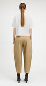 A model viewed from the back wearing a white short-sleeve cropped T-shirt, beige wide-leg cropped trousers, and black ankle boots against a plain light gray studio background.