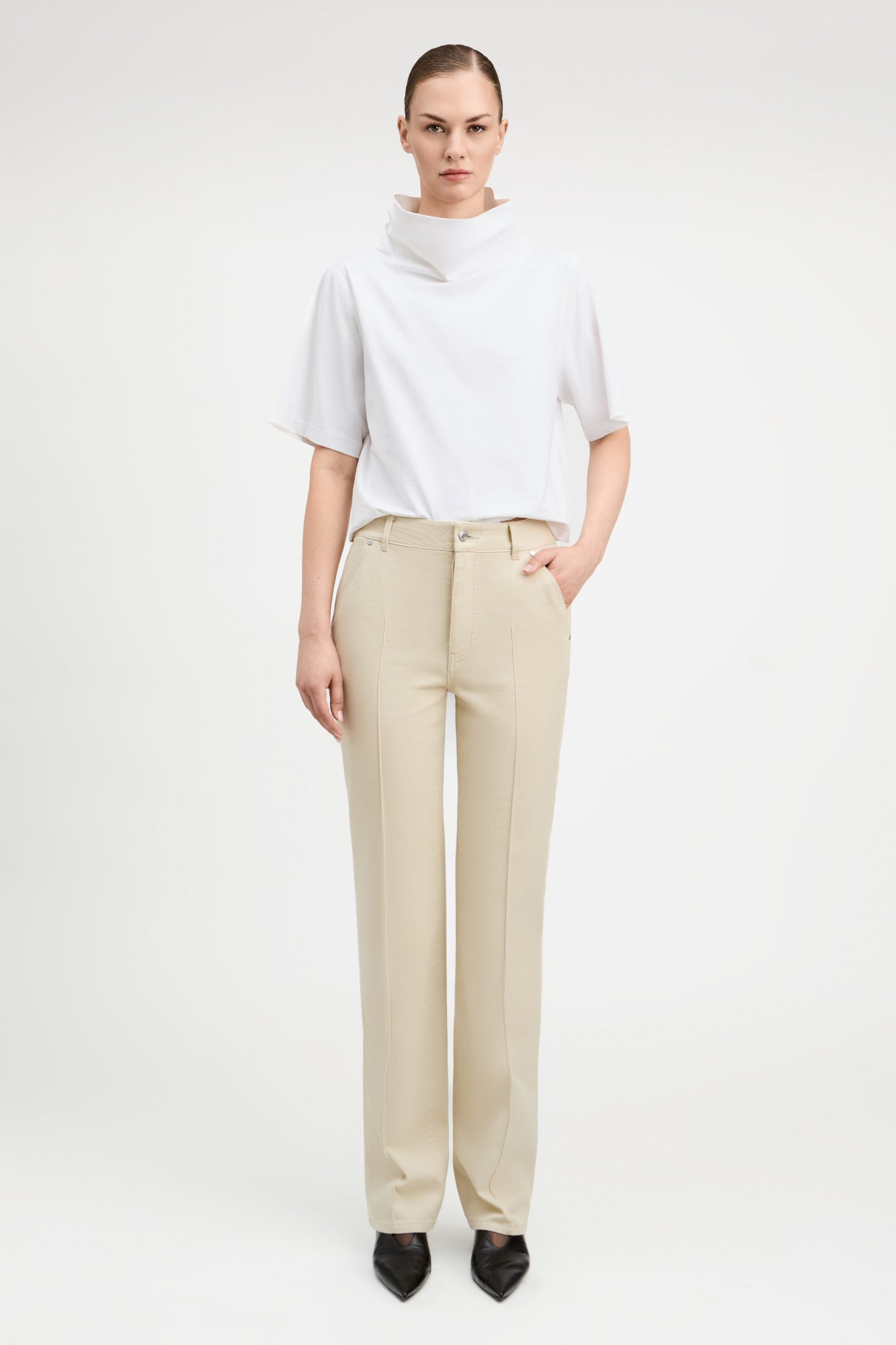 Woman wearing straight cut parchment color jeans with white top.