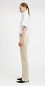 Woman wearing straight cut parchment color jeans with white top, side view. 