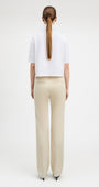 Woman wearing straight cut parchment color jeans with white top, back view.