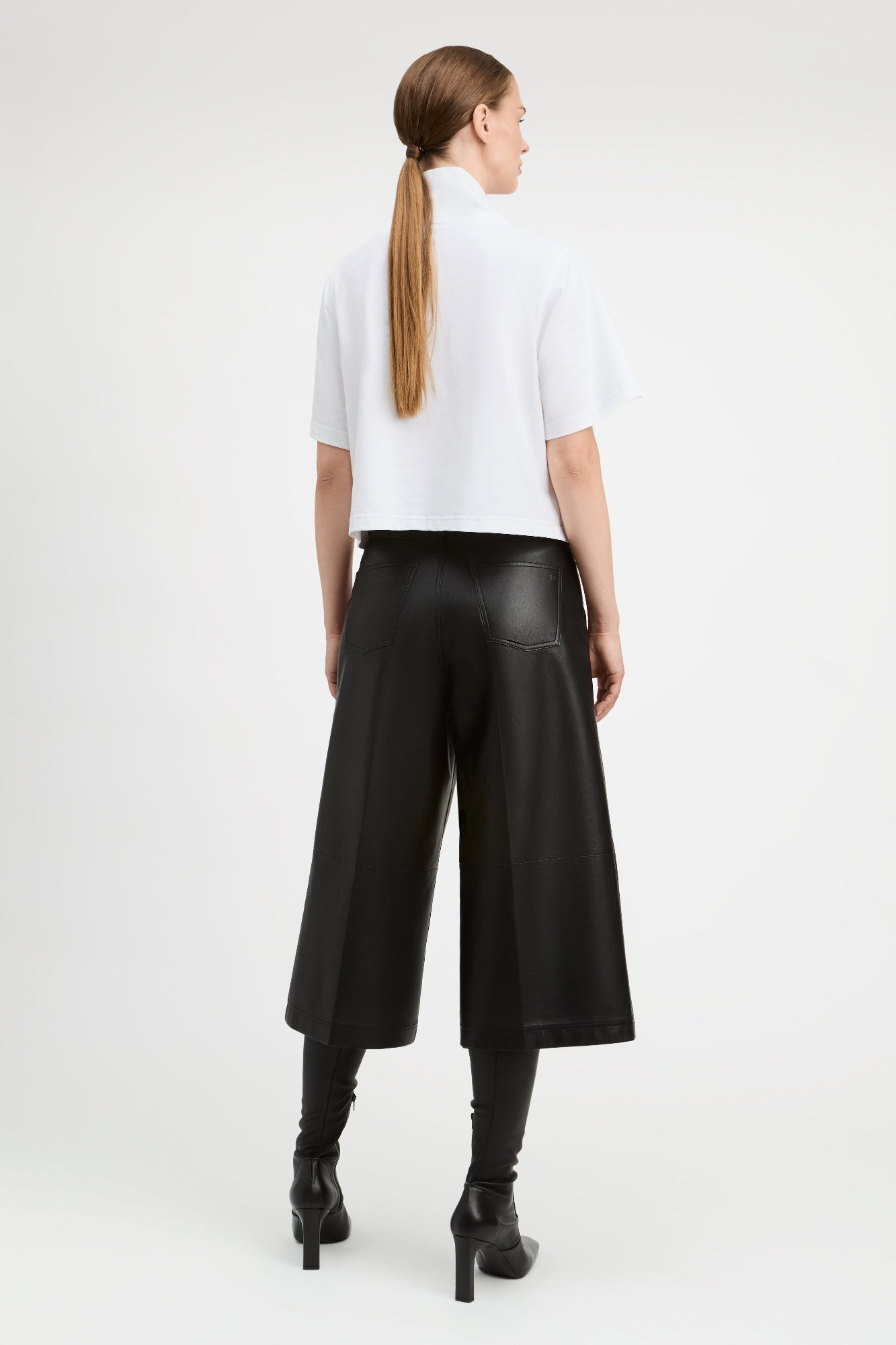 A woman wearing a funnel neckline and a boxy shape back view.