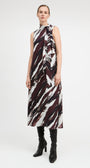 A model stands against a light gray studio background wearing a sleeveless high-neck midi dress with an abstract brushstroke pattern in dark burgundy, black, and off-white. She is also wearing black knee-high boots.