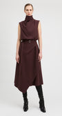 A model stands against a light gray studio background wearing a sleeveless, high-neck, dark brown midi dress with a matching belt and black knee-high boots.