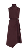 A sleeveless high-neck wrap dress in a deep burgundy color, featuring a structured top section and an asymmetrical draped skirt with a small belt buckle detail at the waist, shown against a plain white background.