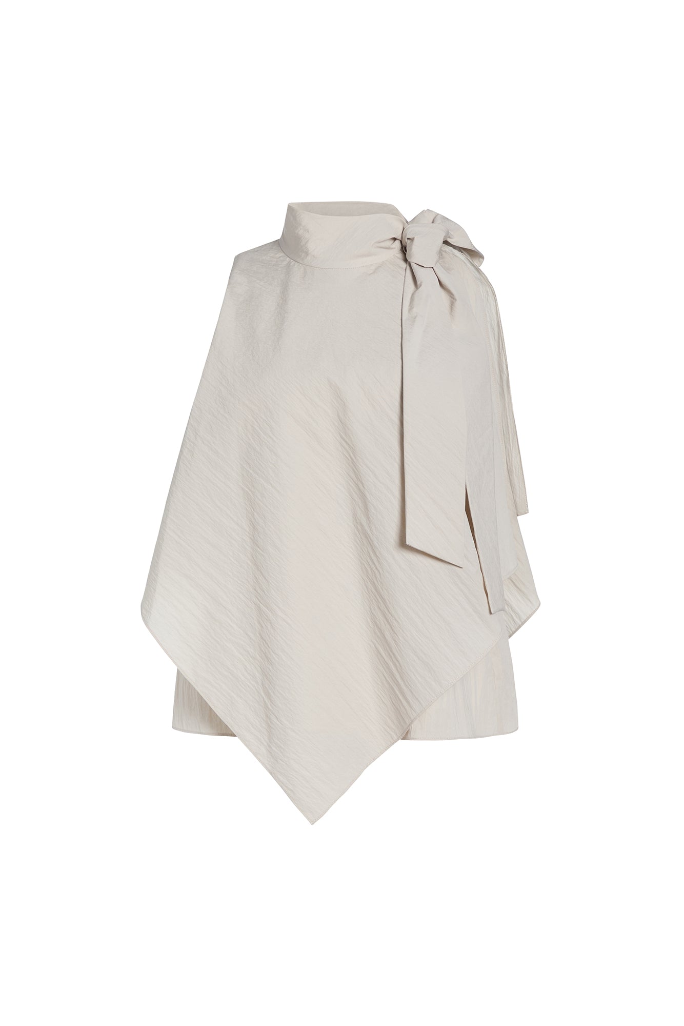 An asymmetrical cream-colored cape top with a high mock neck, textured diagonal crinkle pattern, and a large side bow detail, shown on a plain white background.