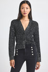 Woman wearing a black sequin blazer with silver buttons on a white background