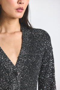 Close-up of a person wearing a black sequin top against a white background