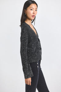 Woman wearing a black sequin top and black pants on a white background