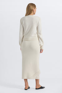 Woman wearing a beige outfit with a matching skirt on a white background