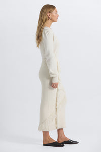 Woman wearing a long cream sweater dress on a white background