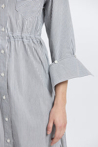 Close-up of a person wearing a black and white striped dress with a white background